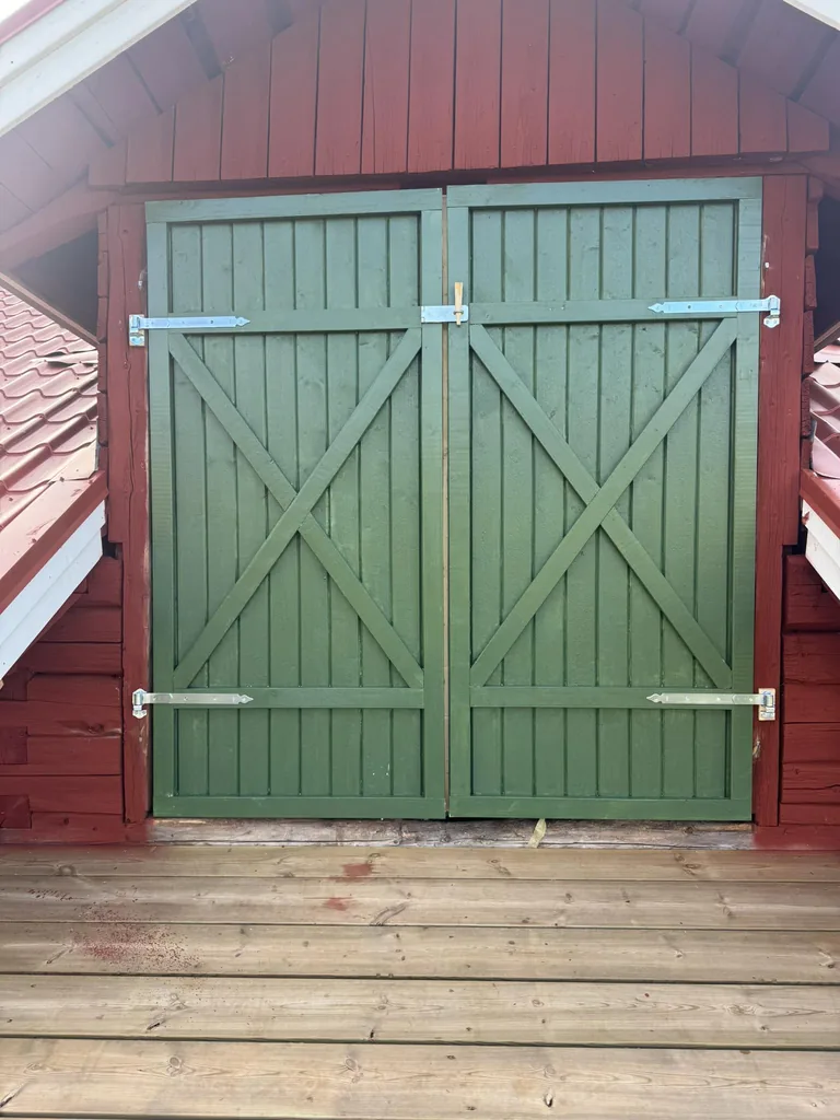 Grön dubbelport i trä på röd byggnad