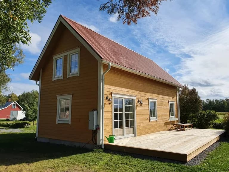 Gult trähus med träfasad och altan som visar färdigt träarbete