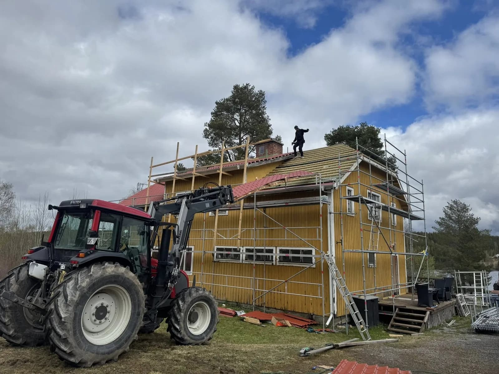 Takbyte och fasadarbete med byggställning på ett gult trähus